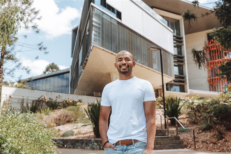 A man in a white t-short standing outside a university