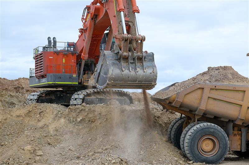 A digger filling a dump truck with critical minerals