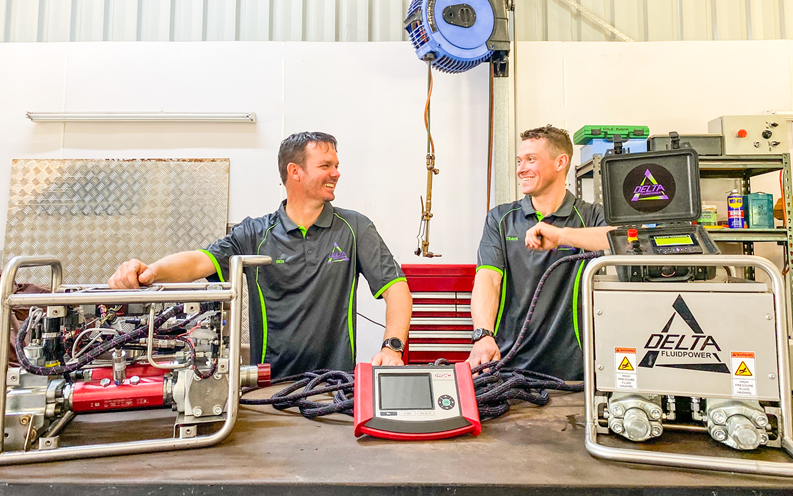 Two workers smiling surrounded by mining technology